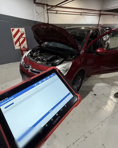 Escáner Launch con el informe de salud de un Citroën C3 con el capot abierto
