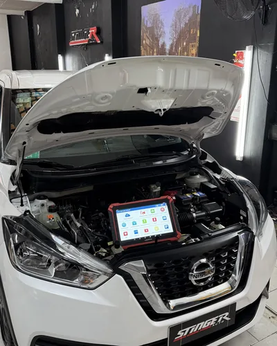 Escáner Launch apoyado en el motor de un Nissan Kicks con el capot abierto